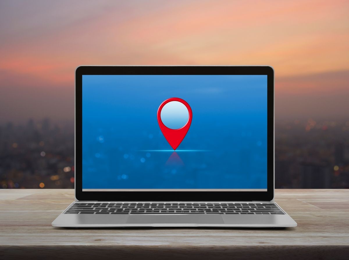 Map pin point location button with modern laptop computer on wooden table over blur of cityscape on warm light sundown, Technology map pointer navigation online concept